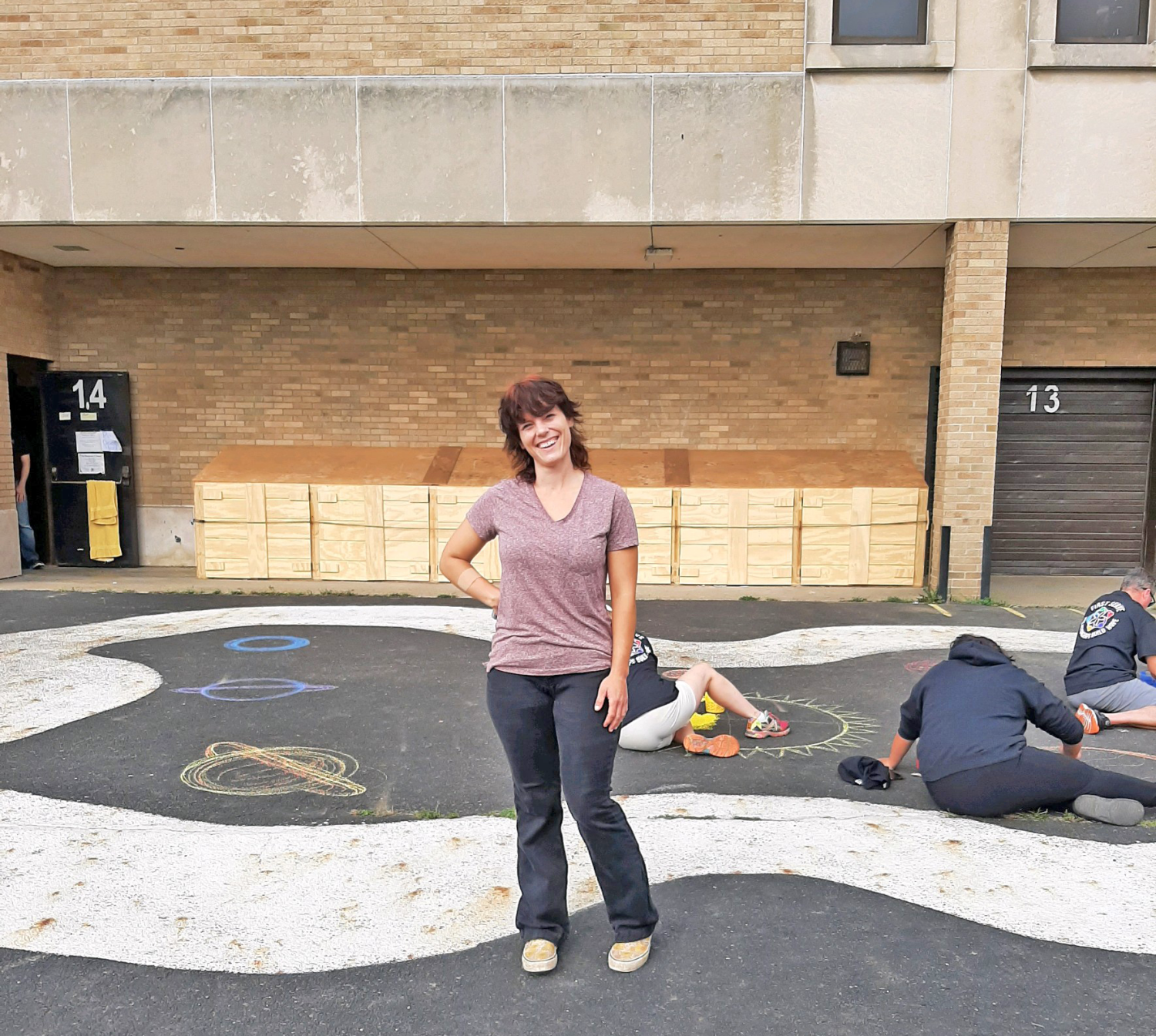 Woman stands smiling in front of painted ground.