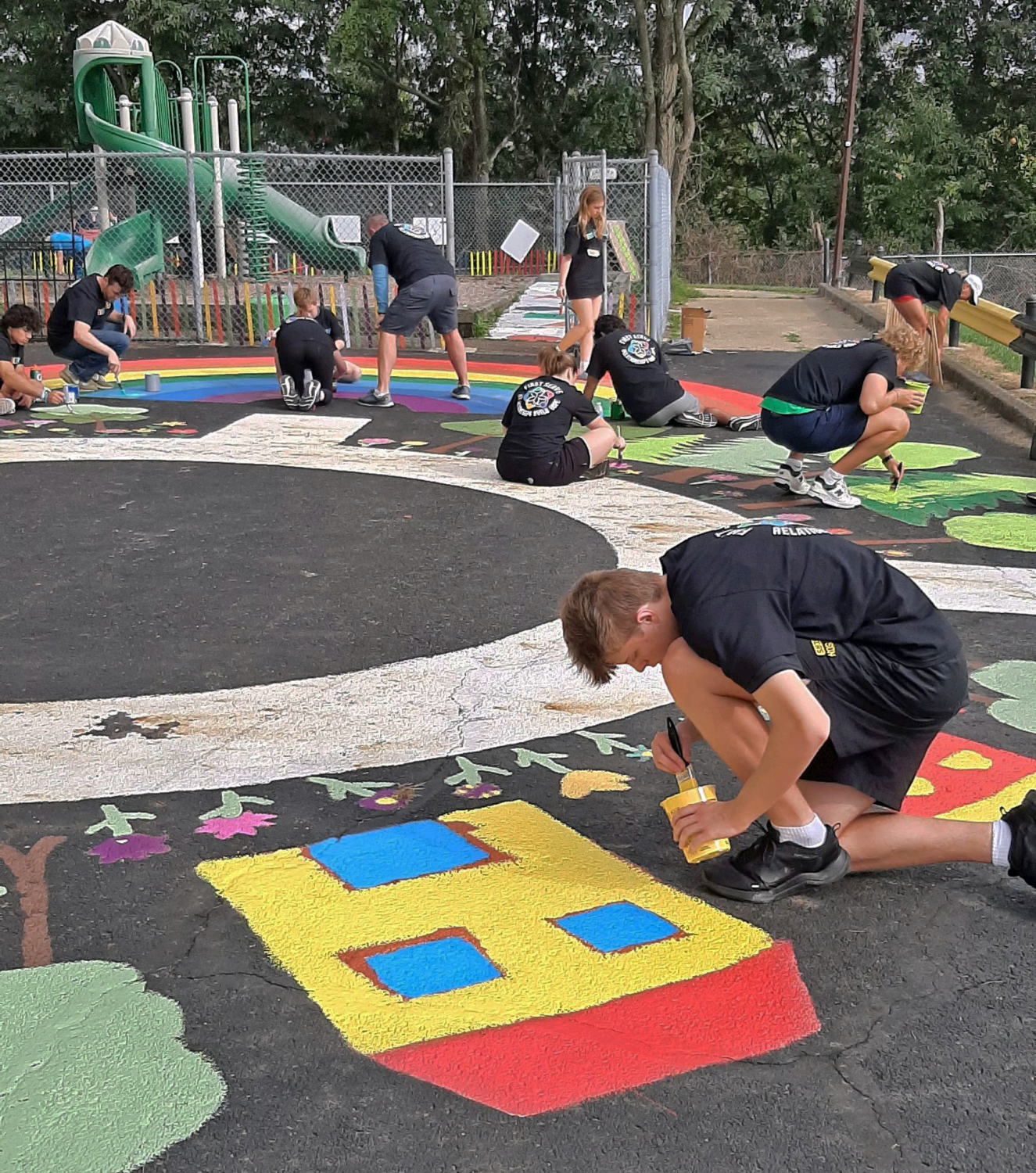 Participants paint colorful designs on the ground. 