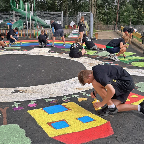 Participants paint colorful designs on the ground. 